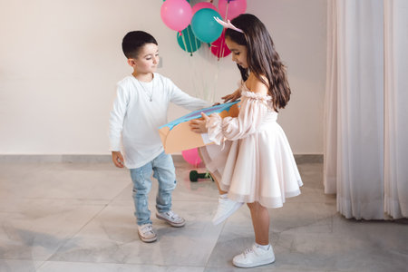 Birthday Surprise: Brothers Gift in Huge Cardboard Box Brings Joy and Smiles to Sisters Morning at Home.Special Birthday Moment with the Girl wearing Crown Headband,looking Embarrassed but Grateful.の写真素材