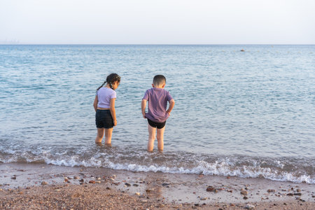 Cute little children playing on the beach. Two kids walking on the seashore in summer day, enjoying...