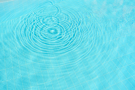 Top view of clear blue pool water with ripples, creating a serene and tranquil atmosphere.