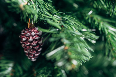 Close-up of a brown pinecone ornament hanging on a green Christmas tree branch.の写真素材