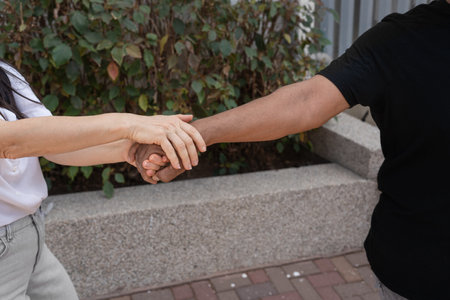 Close-up of hands gently grasping each other, expressing mutual support, care, and solidarity. A strong representation of understanding and cooperation between individuals of different backgrounds.の写真素材
