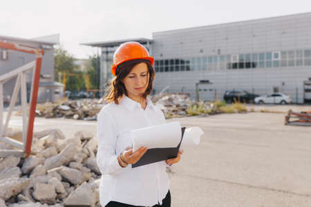Young beautiful woman architect in white shirt and hard hat holding a flip board. woman in hard hat...