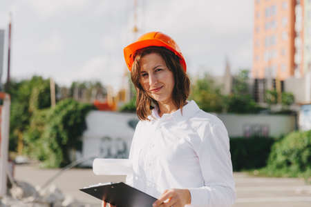 Young beautiful woman architect in white shirt and hard hat holding a flip board. woman in hard hat...