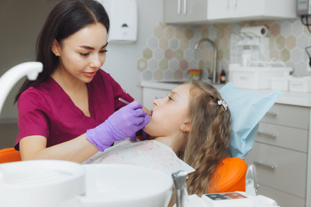 the dentist performs an examination procedure on a cute little girl. Little girl sitting in the dentist's officeの写真素材