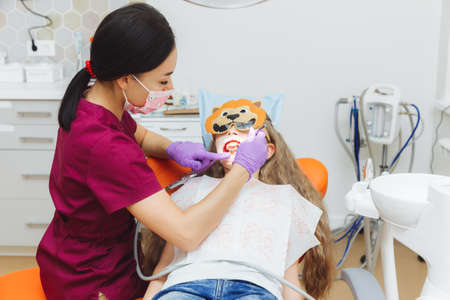 dentist using a rubber dam while examining a patient. little girl with a cheek retractor in her mouthの写真素材