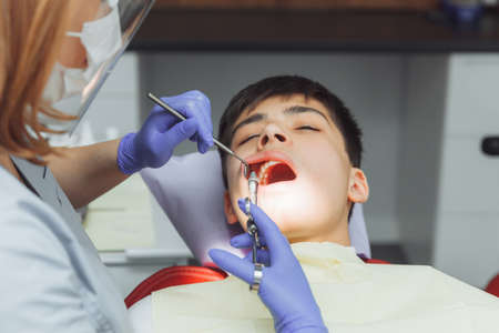 female dentist in protective gear giving an anesthesia injection to a childの写真素材