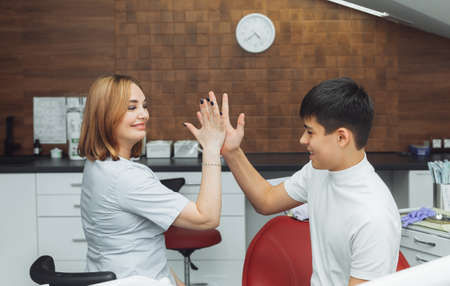 dentist and child after dental treatment in dental clinic office, smiling and giving high five. children's dentistryの写真素材