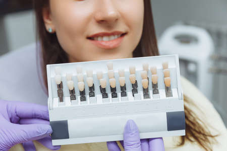 Selection of the correct tooth color for professional cosmetic whitening at the dentist. the doctor selects the teeth for the patient.の写真素材