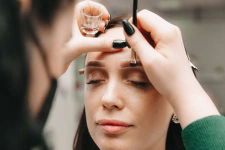 A young woman undergoes an eyebrow correction procedure in a beauty salon, close-up. the girl paints her eyebrows in the salon.の写真素材