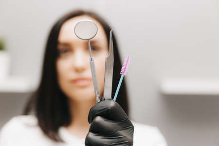 A young girl holds tools for the correction and coloring of eyebrows on a white background. Eyebrow styling conceptの写真素材
