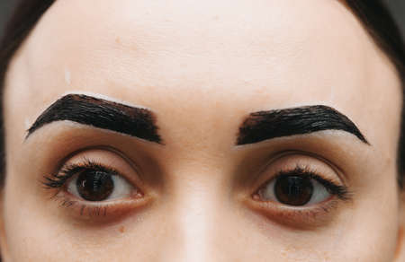 A young woman undergoes an eyebrow correction procedure in a beauty salon, close-up. the girl paints her eyebrows in the salon.の写真素材