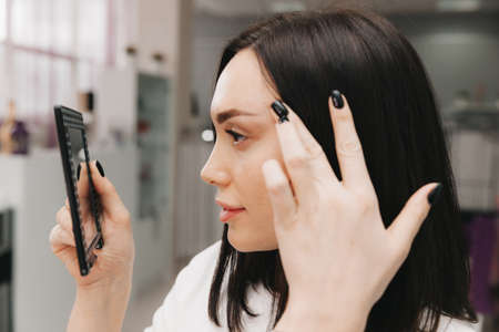 the girl looks in the mirror at her eyebrows.の写真素材