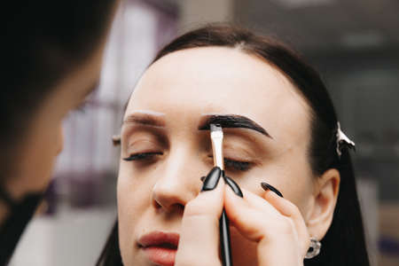 A young woman undergoes an eyebrow correction procedure in a beauty salon, close-up. the girl paints her eyebrows in the salon.の写真素材