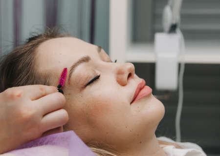 the browist combs the eyebrows with a brush. eyebrow care in the salon.の写真素材
