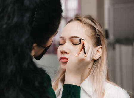 A young woman undergoes an eyebrow correction procedure in a beauty salon, close-up. the girl paints her eyebrows in the salon.の写真素材