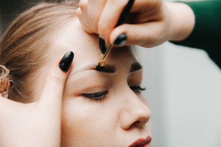 A young woman undergoes an eyebrow correction procedure in a beauty salon, close-up. the girl paints her eyebrows in the salon.の写真素材