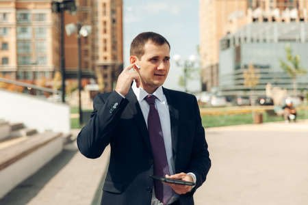 Young handsome businessman in a suit is talking in headphones and smiling. business.の写真素材
