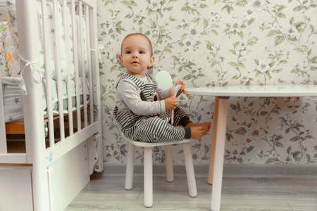 cute baby 11 months old sits on a highchair near the table.の写真素材