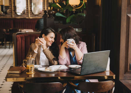 businesswomen sit in a cafe, drink coffee and have a business conversation, discuss business and have fun.の写真素材