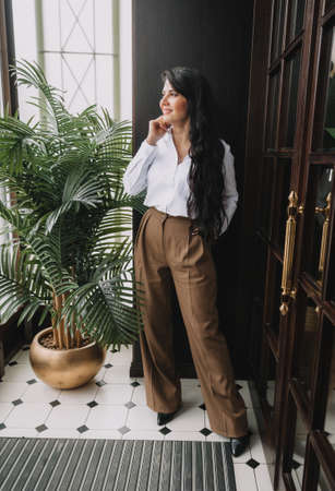 Beautiful business woman in a business suit posing near a glass door.