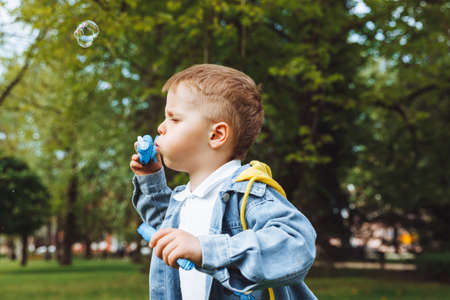 Little boy with soap bubbles in the park. spring sunny day. active games for kids