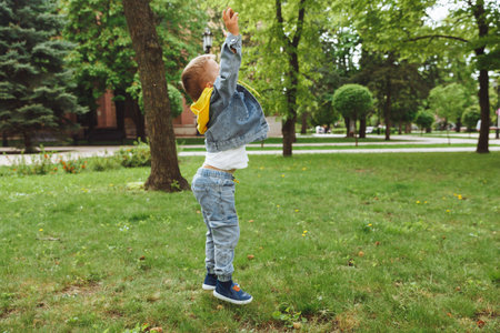 little boy playing ball in the park. hits the ball runs across the field.の写真素材