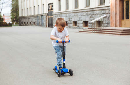 Child on a scooter in the park. A little boy rides a scooter on a sunny day. Active sports for preschoolersの写真素材