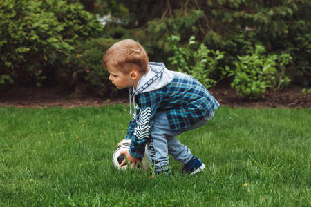 little boy playing ball in the park. hits the ball runs across the field.の写真素材