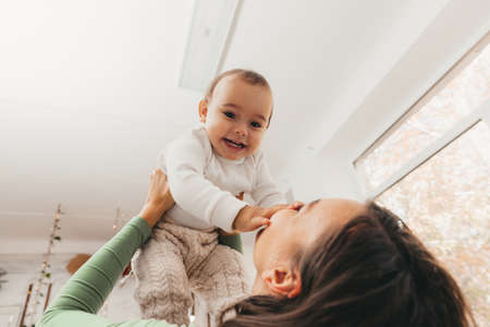 Mother and daughter are playing and having fun. Home interior, bed, a woman throws a child on the bed.の写真素材