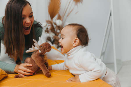 A young mother with a baby, relaxing and playing together in bed, a lazy morning, a warm and cozy scene. selective focus.の写真素材