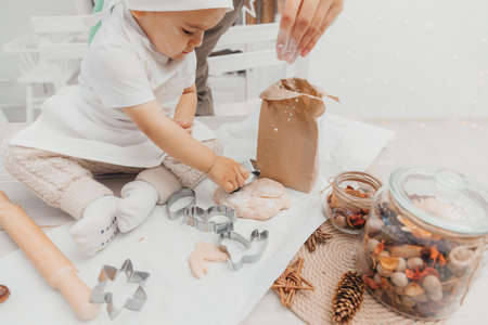 Mother and baby are baking in the kitchen. Happy mom kisses her child, they have fun and prepare food. The kid has a chef's hat.の写真素材