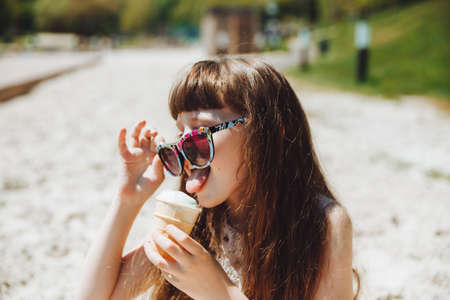 Happy little girl eating ice cream on the beach in summer. summer holidaysの写真素材