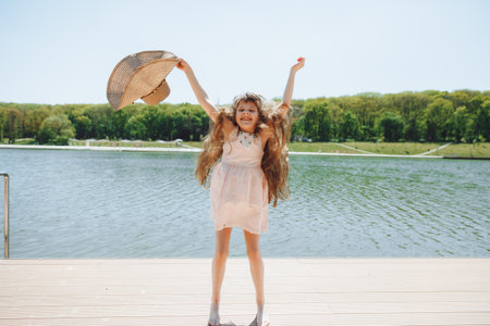 A cute little girl is standing on the pier looking at the beautiful lake. child jumping and having...