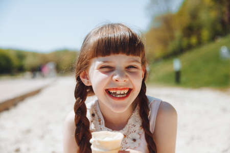 Happy little girl eating ice cream on the beach in summer. summer holidaysの写真素材