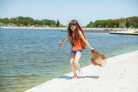 Happy little girl with long hair runs along the beachの写真素材