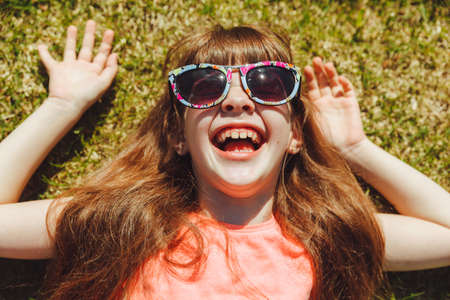Top view of a happy girl, smiling and lying on the green grass on a summer day in the park