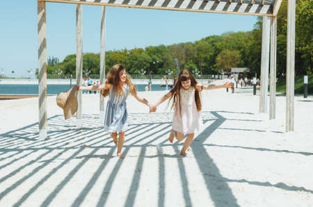 two happy little girls run merrily and joyfully along the beach, rejoice and have fun.の写真素材
