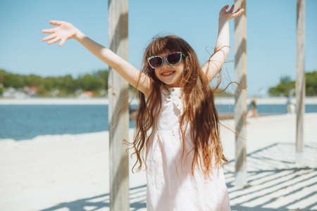 little girl jumping on the beach on the shore of the city beach in the summer holidaysの写真素材