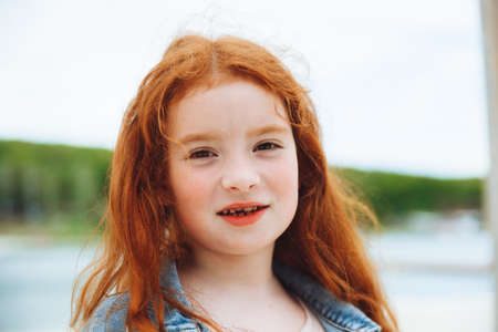 portrait of a cute charming little red-haired caucasian girl. concept of happy lifestyle in childhoodの写真素材