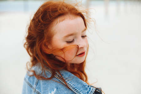 portrait of a cute charming little red-haired caucasian girl. concept of happy lifestyle in childhoodの写真素材