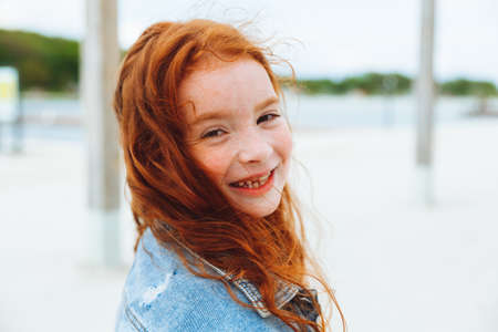 portrait of a cute charming little red-haired caucasian girl. concept of happy lifestyle in childhoodの写真素材