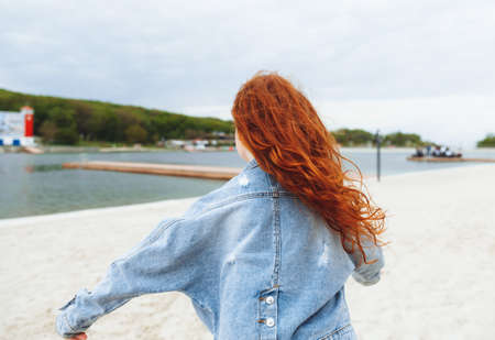 Happy little girl with red hair runs along the beach. child on the beachの写真素材