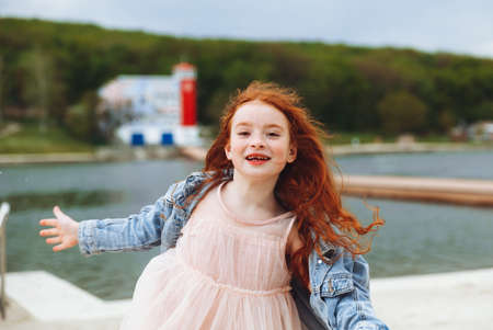 Happy little girl with red hair runs along the beach. child on the beach