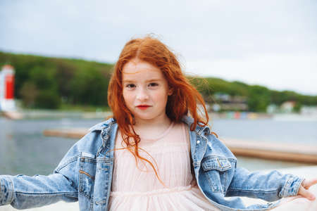 Happy little girl with red hair runs along the beach. child on the beachの写真素材