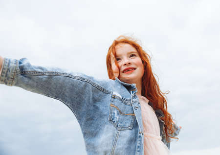 Happy little girl with red hair runs along the beach. child on the beach