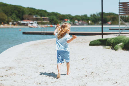 little happy blond boy runs and has fun on the beachの写真素材