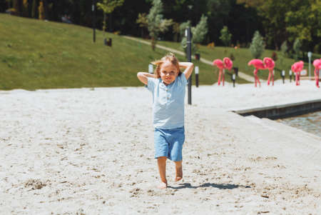 little happy blond boy runs and has fun on the beachの写真素材
