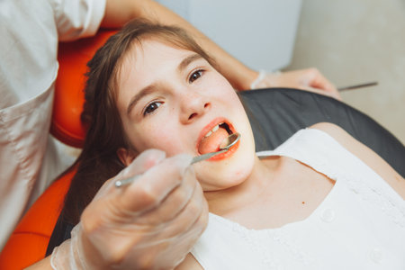 the dentist performs an examination procedure on a cute little girl. Little girl sitting in the dentist's officeの写真素材