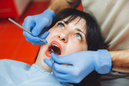 A male doctor examines the oral cavity of a young patient sitting in a dentist's chair in the office next to the dentist. the concept of healthy teeth.の写真素材