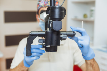The dentist examines the patient's mouth with a dental microscope. dental treatment. the concept of...